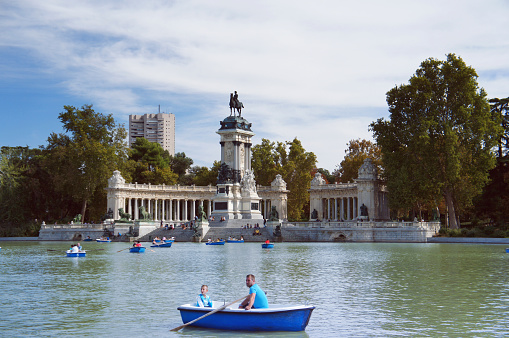 Madrid, Spain - September 21, 2014: People walk on boats at Buen Retiro Park central pond in summer sunny day in Madrid. 