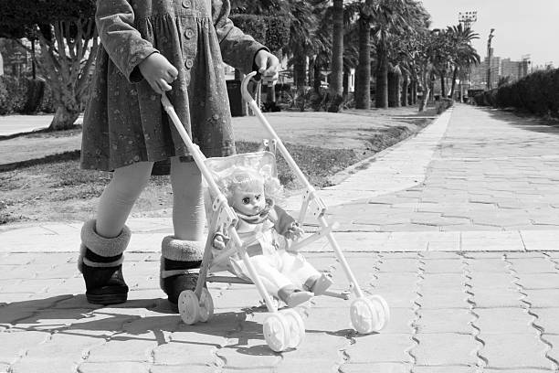 istock Little girl pushing baby doll in stroller 519546812