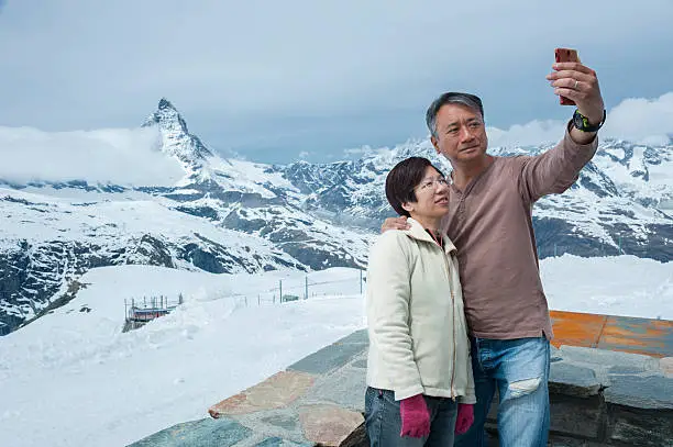 Asian tourist taking selfie on Mountain Matterhorn, Zermatt, Switzerland