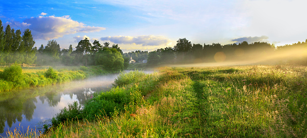 the panorama of a summer landscape with sunrise, fog and the river