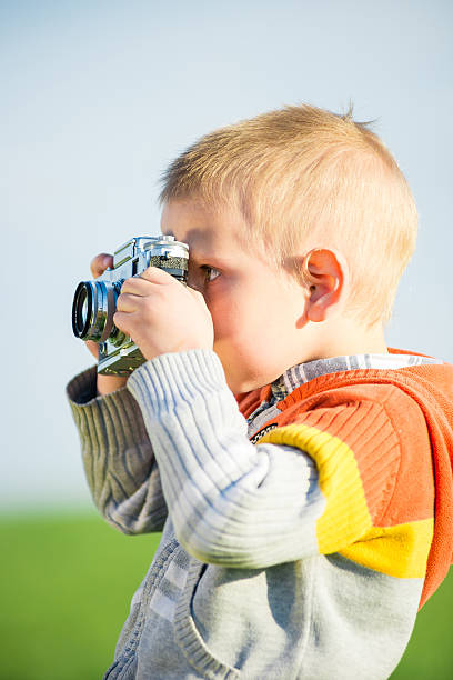 istock Little boy with an old camera shooting outdoor 519549210