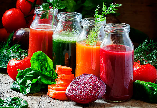 Four kind of vegetable juices: red, burgundy, orange, green Four kind of vegetable juices: red, burgundy, orange, green, in small glass bottles, fresh vegetables and herbs, vintage wooden background, selective focus detox stock pictures, royalty-free photos & images