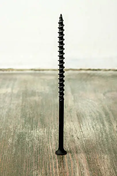 Black screw on wooden background, macro shot