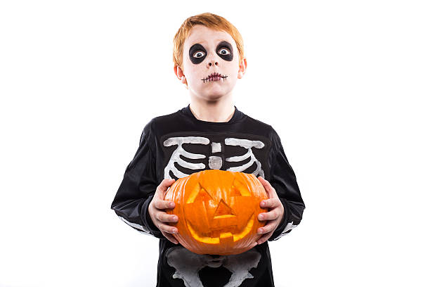 red pêlo menino em traje de esqueleto segurando uma abóbora.  halloween - figurino - fotografias e filmes do acervo
