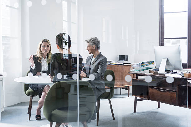 istock Three business people having meeting behind glass partition 519556450