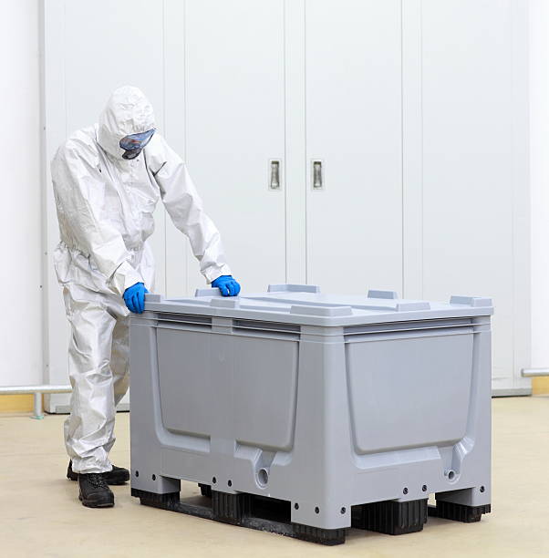 istock worker in coveralls, mask and goggles  large  plastic container 519557147
