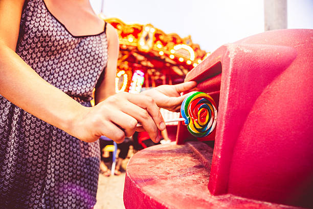 Young woman throw a lollipop into the trash at the amusement park.