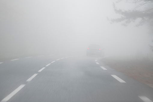 Very thick fog on the rural road, with lighthouse of a car