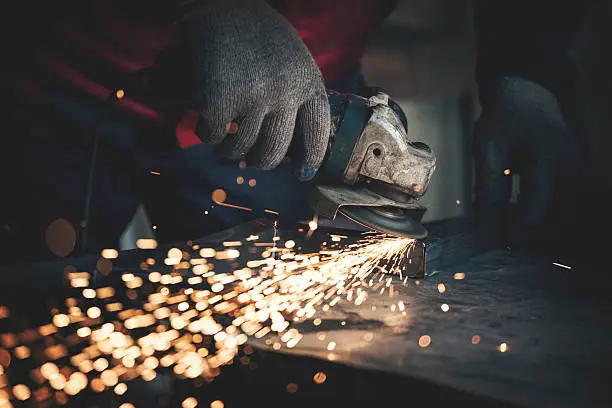 Worker grinding metal. Shallow DOF. Developed from RAW; retouched with special care and attention; Small amount of grain added for best final impression.16 bit Adobe RGB color profile.