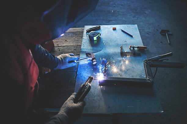istock Man welding steel bars rear view 519575762