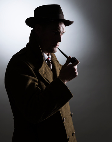 A dark and mysterious 1940's retro-styled silhouette gumshoe detective with a curious and mildly suspicious facial expression is holding his smoking pipe near his lips. He is wearing a long double-breasted overcoat with the collar turned up; a garish flower design necktie; and a dark fedora hat.