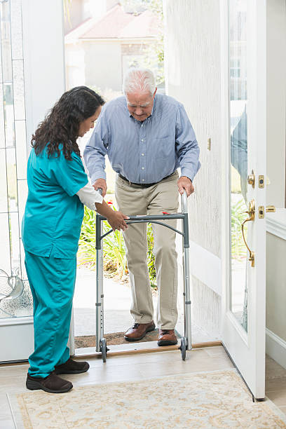 istock Home healthcare worker helping elderly man with walker 519579986