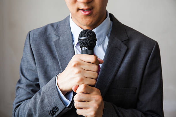 Young talking man holding microphone without confidence Young talking man holding microphone without confidence on isolated white background announce stock pictures, royalty-free photos & images