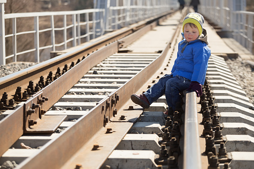 Portrait of a little boy sitting on the rails in the daytime. Belarus