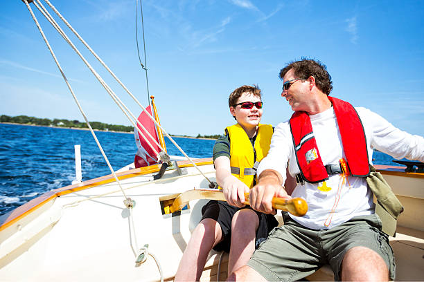 Father and Son Father and son sailing on sailboat. life jackets stock pictures, royalty-free photos & images