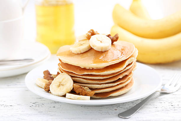 Tasty pancakes with banana and walnut on white wooden background stock photo