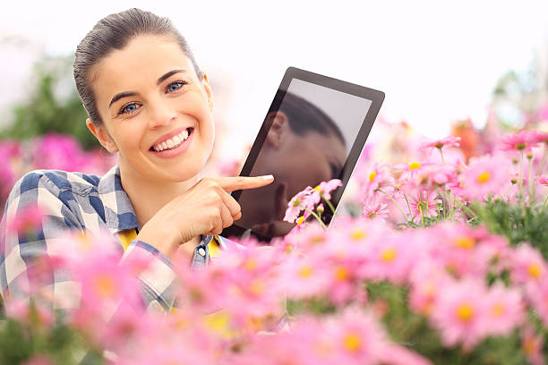 istock springtime, woman with tablet smiling in garden flowers 519614652