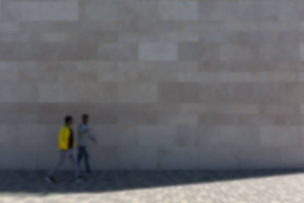 istock People in front of stone wall on pedestrian path, blurred, picture background 519615994