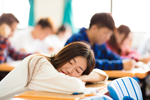 tired and asleep college student  for exam in classroom