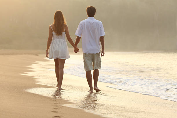 istock Couple walking and holding hands on the sand 519620231