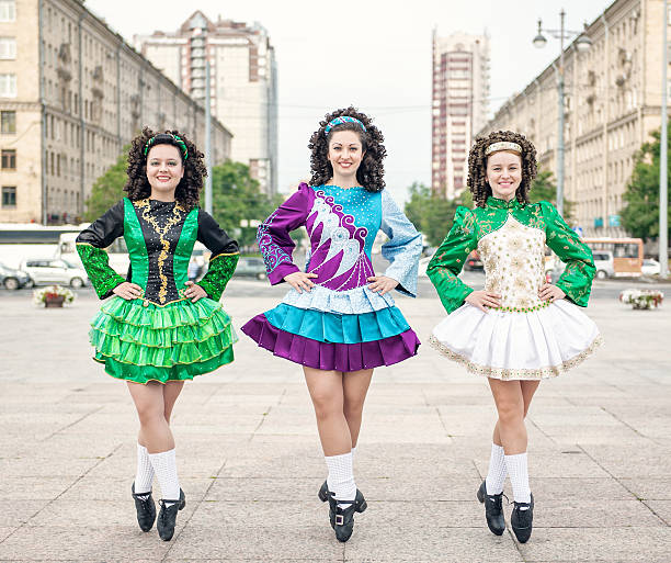 Three women in irish dance dresses and wig posing outdoor