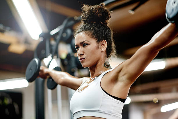 Life can be tough but so can you Shot of a young woman working out with weights in the gym weight training stock pictures, royalty-free photos & images
