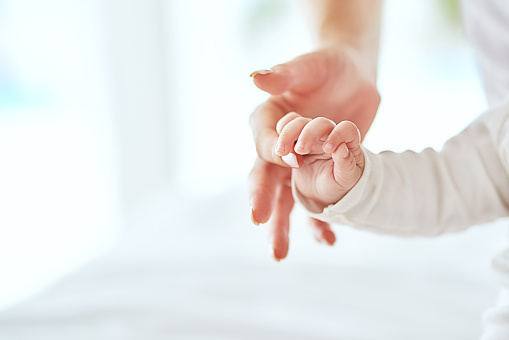 Cropped shot of a mother holding her baby’s hand