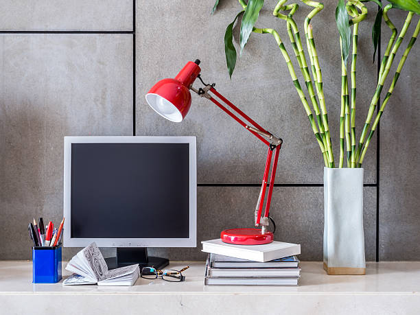 Modern office desk with computer, lamp and vase of flowers stock photo