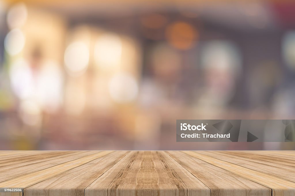 Wooden board empty table blur in coffee shop. Wooden board empty table in front of blurred background. Perspective brown wood over blur in coffee shop - can be used for display or montage your products.Mock up your products.Vintage filter. Backgrounds Stock Photo