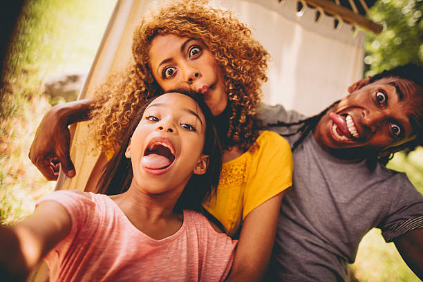 lovely african-american family making silly faces and posing - een gek gezicht trekken stockfoto's en -beelden