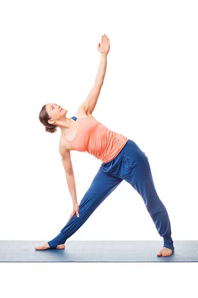 Beautiful sporty fit woman practices yoga asana utthita trikonasana - extended triangle pose beginner variation isolated on white background