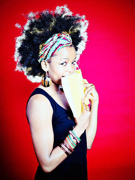 istock Cute Afro-haired woman peeps flirtatiously over book 519643839