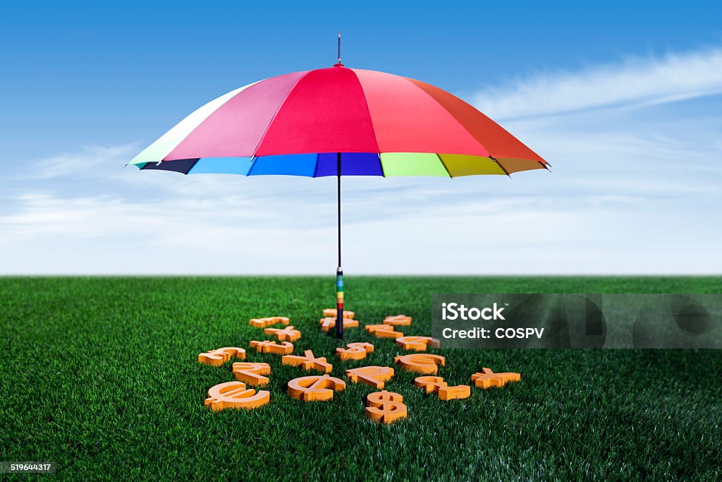 Currency units with colourful umbrella Currency units under the colourful umbrella on green grass British Currency Stock Photo
