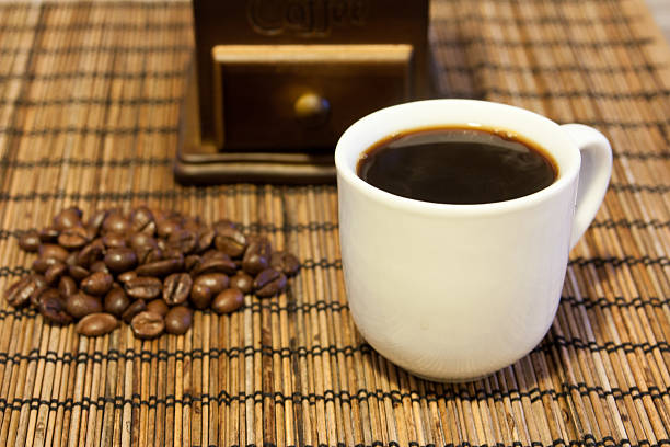coffee beans with cup of coffee with mill on background