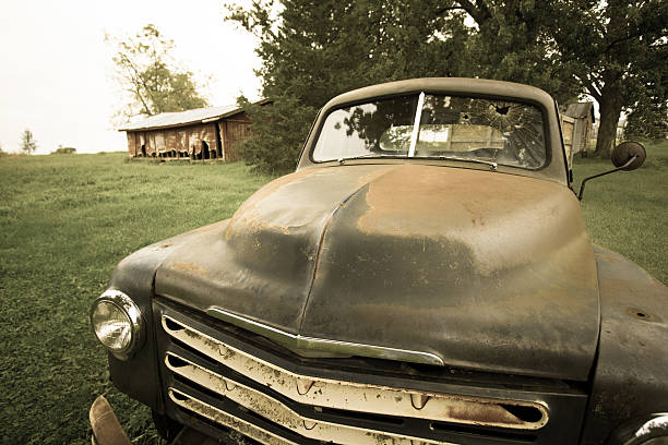 Midwest Scene: Rusty Green Pickup and Old Red Barn A Midwest USA scene: rusty vintage pickup truck with shattered windshield in the foreground and an old barn in the background. Processed as "Aged Photo" in Lightroom. distressed rusty vintage pickup truck close up detail stock pictures, royalty-free photos & images