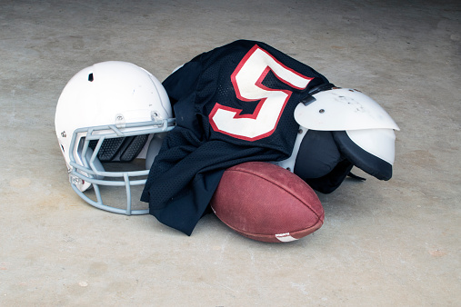 A low angle view of a leather American Football spotted next to a white side line within a yard of a blue end zone.