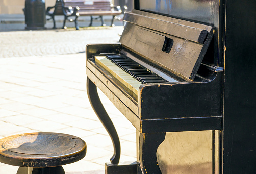 Old wooden piano on the sunny old city street available for passers by.