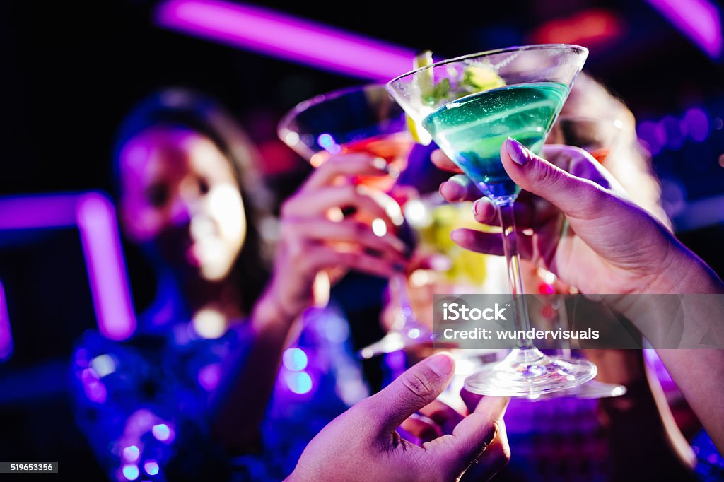 Young friends toasting with drinks during night club party Close up of young adult hands holding colored cocktails and toasting in a night club Nightclub Stock Photo