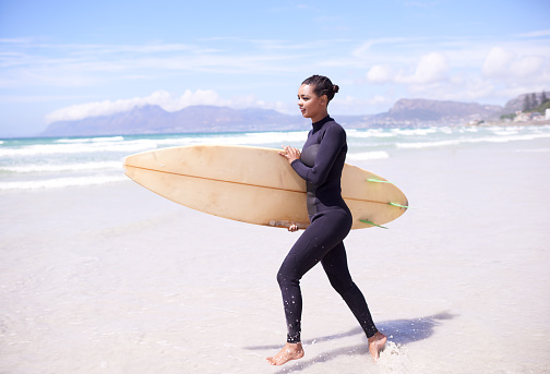 Shot of a young woman at the beach with a surfboard