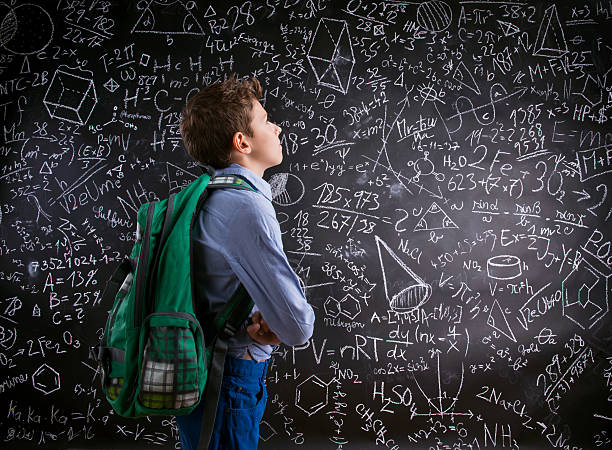 istock Boy  with schoolbag against big blackboard with mathematical sym 519656508