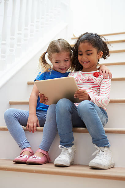 istock Two Girls Sitting On Staircase Using Digital Tablet 519659714