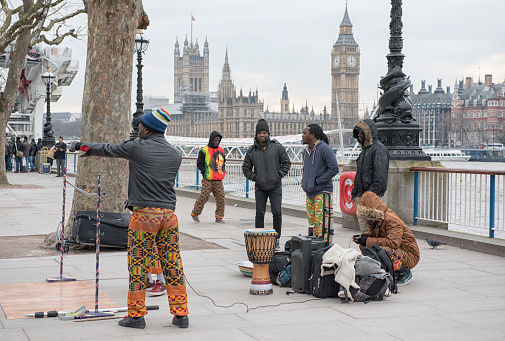 London, England - February 27, 2016: Street performers in London, with tourists and Big Ben in the background