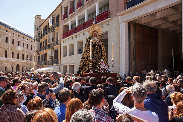 Malaga, Spain - March 24, 2016: a statue of the Virgin Mary is transported towards the temple of the Sepulcro brotherhood (open doors), just to the right of the temple of Estudiantes Brotherhood. This small procession is opart of the holy week rituals of the brotherhood and attracts many spectators. 