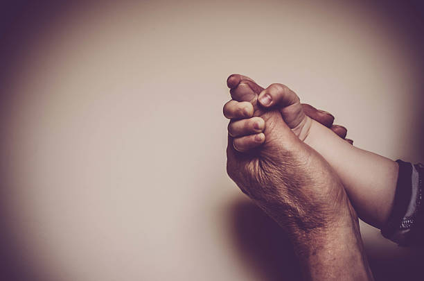 Father and child holding hands against wall background stock photo