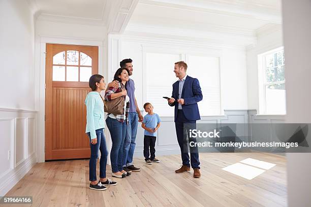 Real Estate Agent Showing Hispanic Family Around New Home Stock Photo - Download Image Now