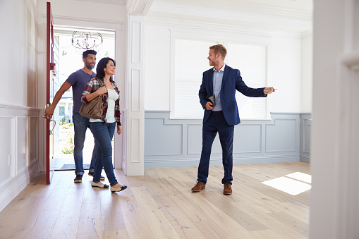 Real Estate Agent Showing Hispanic Couple Around New Home