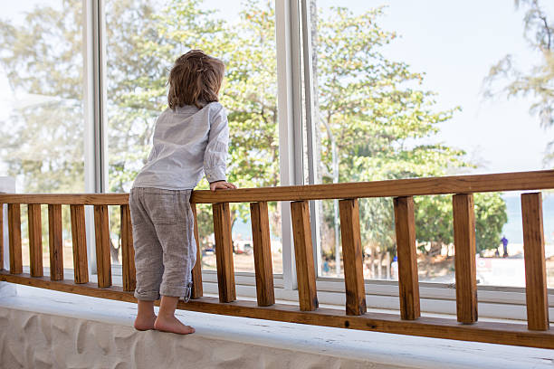 istock Rear view of a small boy looking through window. 519664314
