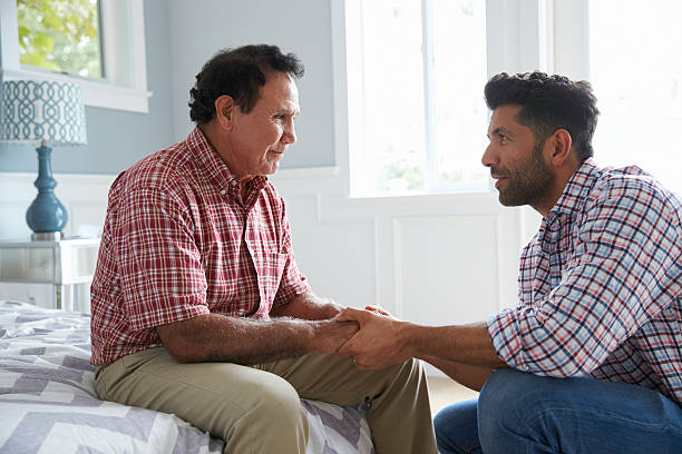 Adult Son Comforting Father Suffering With Dementia Adult Son Comforting Father Suffering With Dementia DisruptAgingCollection stock pictures, royalty-free photos & images