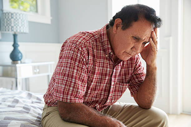 senior ispanico uomo seduto sul letto che soffrono di depressione - senior adult depression dementia alzheimers disease foto e immagini stock