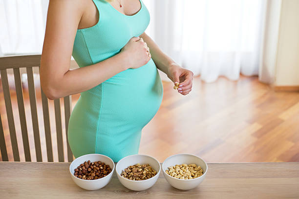 Pregnant woman with 3 bowls of nuts on the table Pregnant woman with 3 bowls of nuts on the table  omega 3 photos stock pictures, royalty-free photos & images